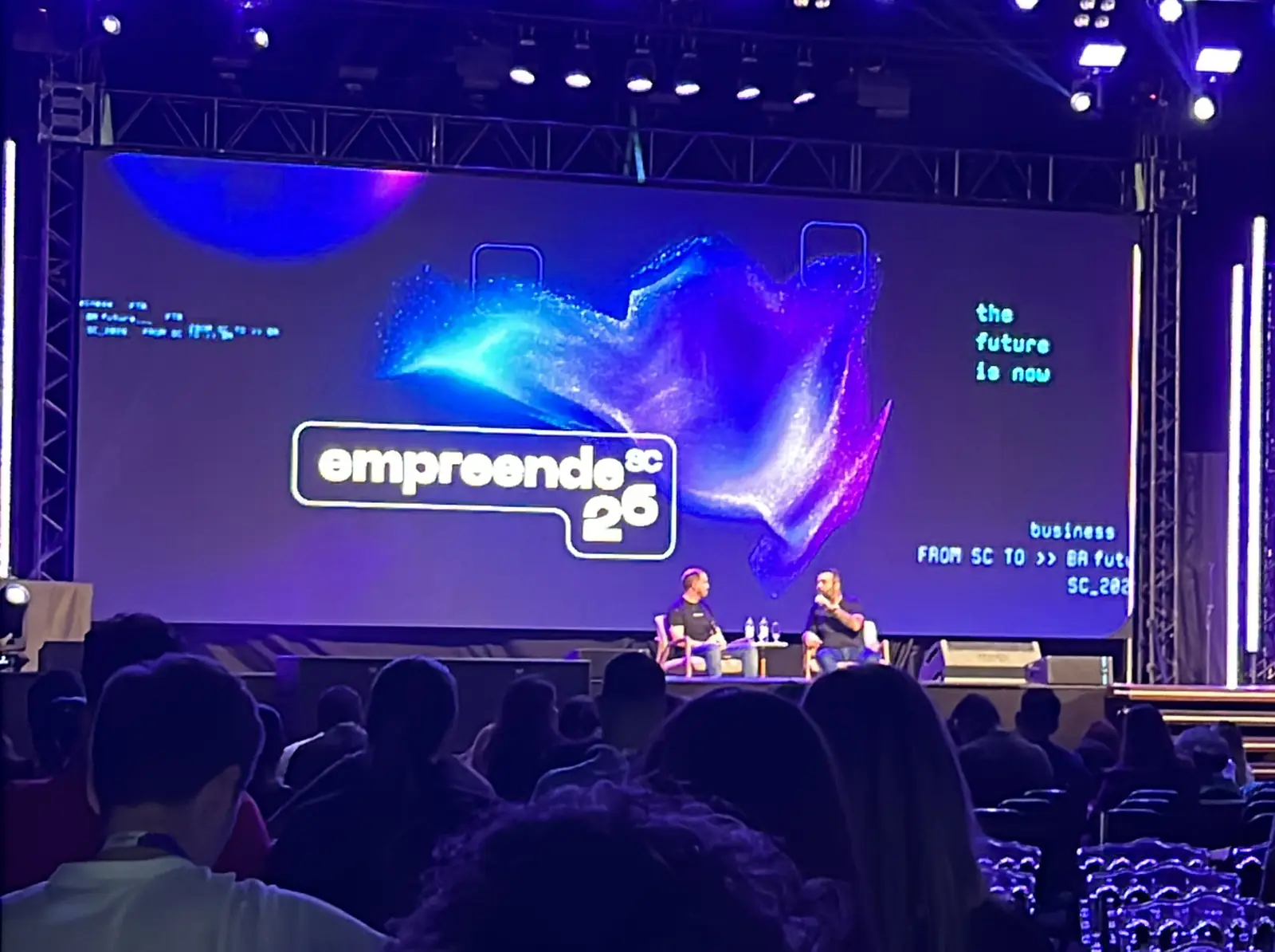 Plateia diante do palco do Empreende SC, com telão e iluminação em azul e roxo